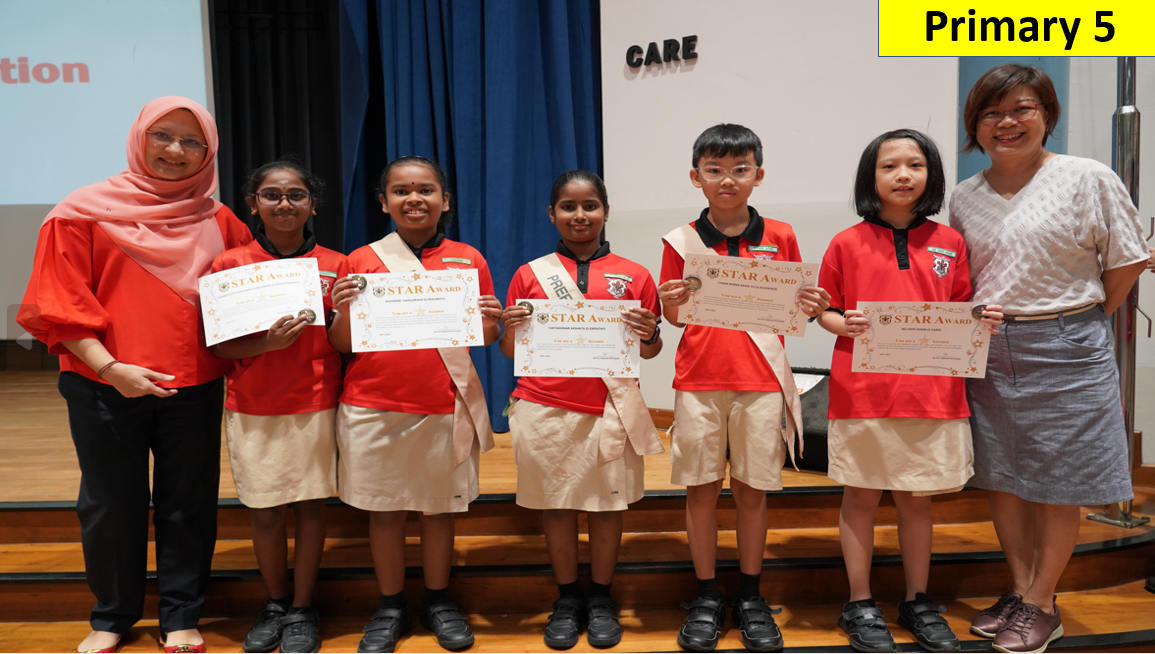 Five Primary 5 students in red uniforms hold Star Award certificates, flanked by two teachers on a stage.